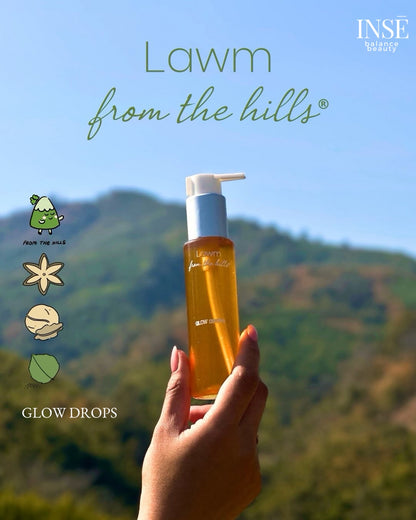 Hand holding a bottle of 'Lawm from the Hills' Glow Drops with a mountainous background